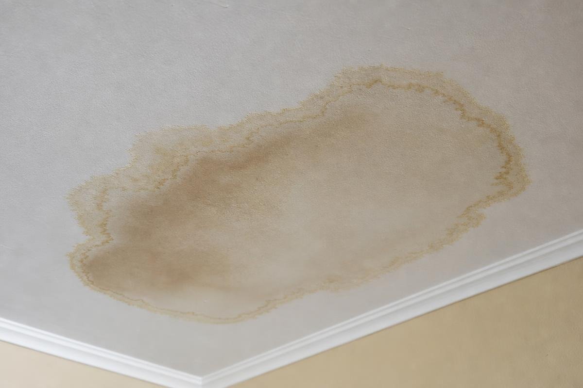 brown and yellow ceiling water stain showing signs of water damage in a home